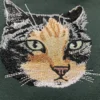 Close-up of a thread-painted calico cat face with green eyes embroidered on a forest green sweatshirt