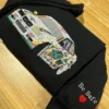 Black hoodie on a wooden table with the graffiti sports car on the chest and Be Safe with a red heart on the cuff