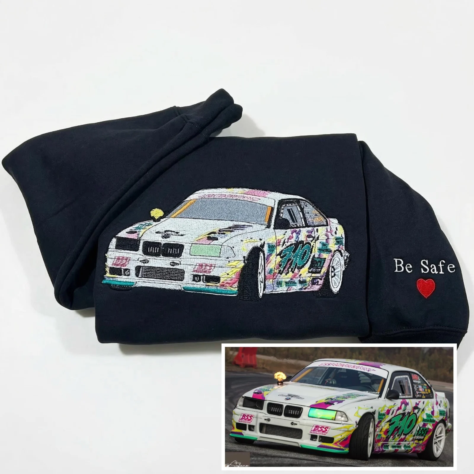 Black hoodie with a white graffiti-livery sports car embroidered from a photo and Be Safe with a red heart on the sleeve