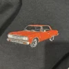 Close-up of an embroidered orange classic coupe with chrome trim and black tyres on black fleece
