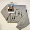 Folded grey sweatshirt with two framed line-art portraits stitched in black and the source photo print on top