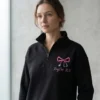 Custom nurse bow embroidered quarter zip in black with pink script name and credentials front view