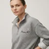 Custom embroidered nurse name and credentials on heather grey quarter zip showing left chest placement