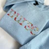 Light blue crewneck with the floral embroidered word nurse running diagonally across the chest