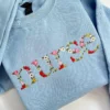 Light blue sweatshirt with the word nurse spelled in lowercase letters made of embroidered roses and daisies