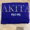 Folded sweatshirt with large floral AKITA letters in blue, white, pink and yellow flowers above mom