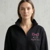 Woman wearing nurse bow stethoscope embroidered quarter zip in black with pink bow and custom name