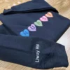Navy sweatshirt on a wooden table with candy heart NURSE embroidery and Liway RN along the sleeve