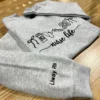 Heather grey nurse life sweatshirt folded on a wooden table with Liway RN embroidered in black on the sleeve
