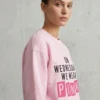 Woman wearing On Wednesdays We Wear Pink embroidered sweatshirt in light pink side view
