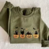 Military green black cat Halloween sweatshirt laid flat on a cream blanket