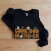 Folded black Code Boo in the ER Halloween sweatshirt on a wooden table