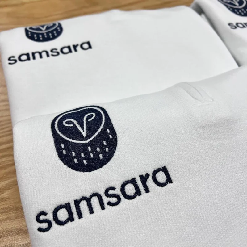 White quarter-zips with a navy owl icon and lowercase company wordmark embroidered on the left chest