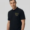 Man in a black polo shirt with a gold embroidered text placeholder on the chest, studio background