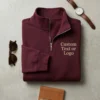 Maroon quarter-zip flat-lay with sample text Custom Text or Logo embroidered in tan on the left chest