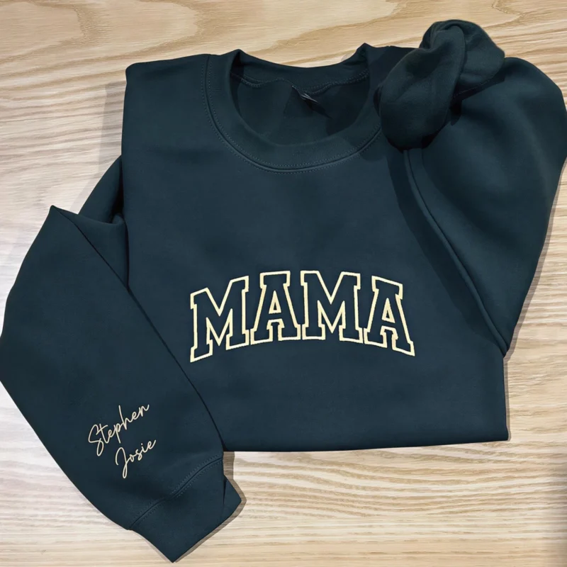 Forest green MAMA sweatshirt on a wooden floor with Stephen and Josie embroidered in cream script on the sleeve