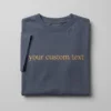 Folded slate blue T-shirt with the words your custom text embroidered in tan serif lettering, flat-lay