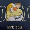 Dad portrait embroidery on a navy sweatshirt: gold outline D and D framing a dad and child in place of the A, EST. 2018