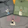Three embroidered DAD portrait tops in dark grey, military green and grey, each with a dad holding his baby