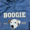 Close-up of a stitched white dog with brown ears under the name BOOGIE, with est. and 2021 on either side