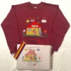 Maroon crewneck laid flat with the embroidered child’s house drawing, colouring pencils and the original sketchbook