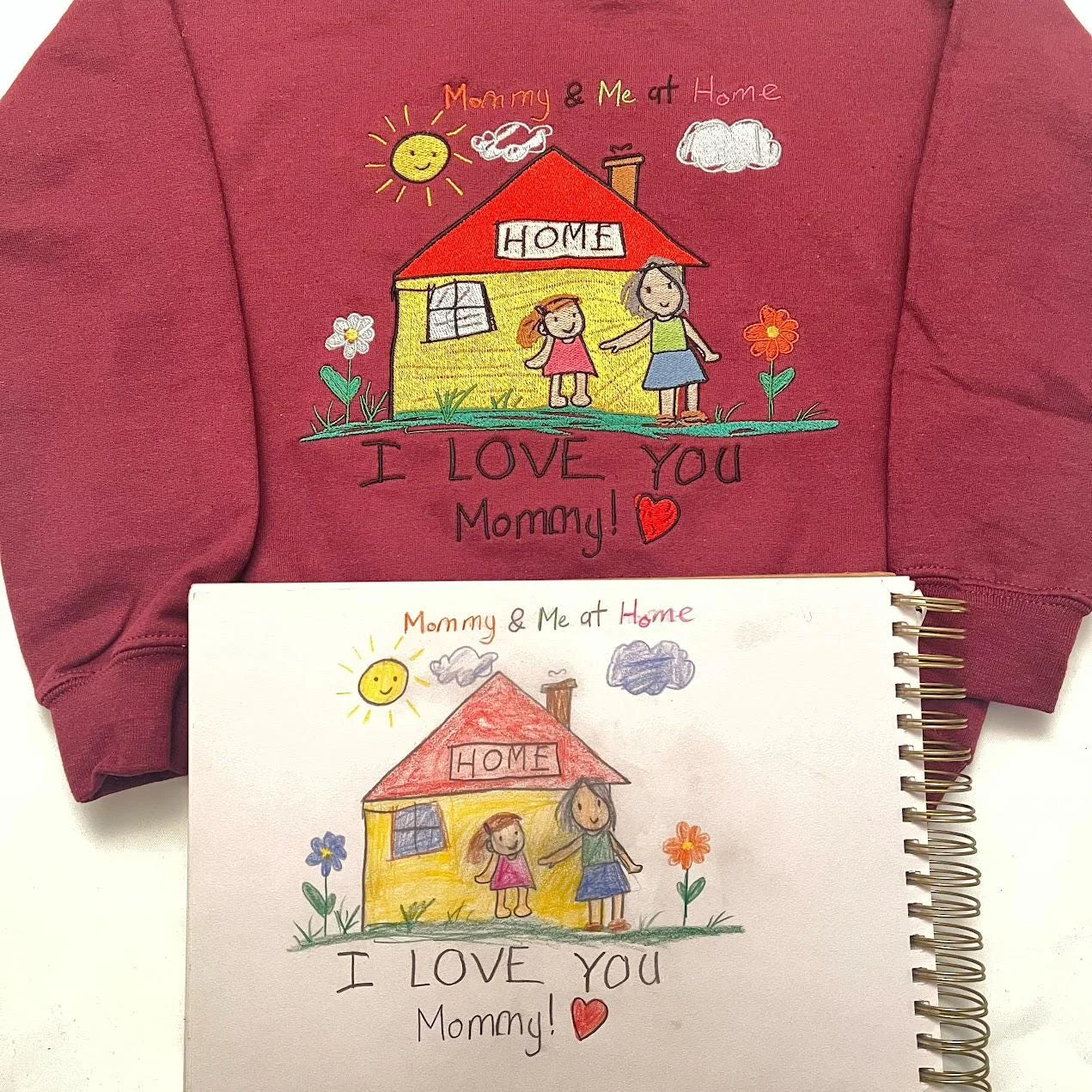 Maroon sweatshirt with a child’s house, mom and daughter and I LOVE YOU Mommy stitched, above the original drawing