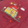 Close-up of the stitched drawing: yellow house with red roof, two smiling figures, sun, cloud and flowers
