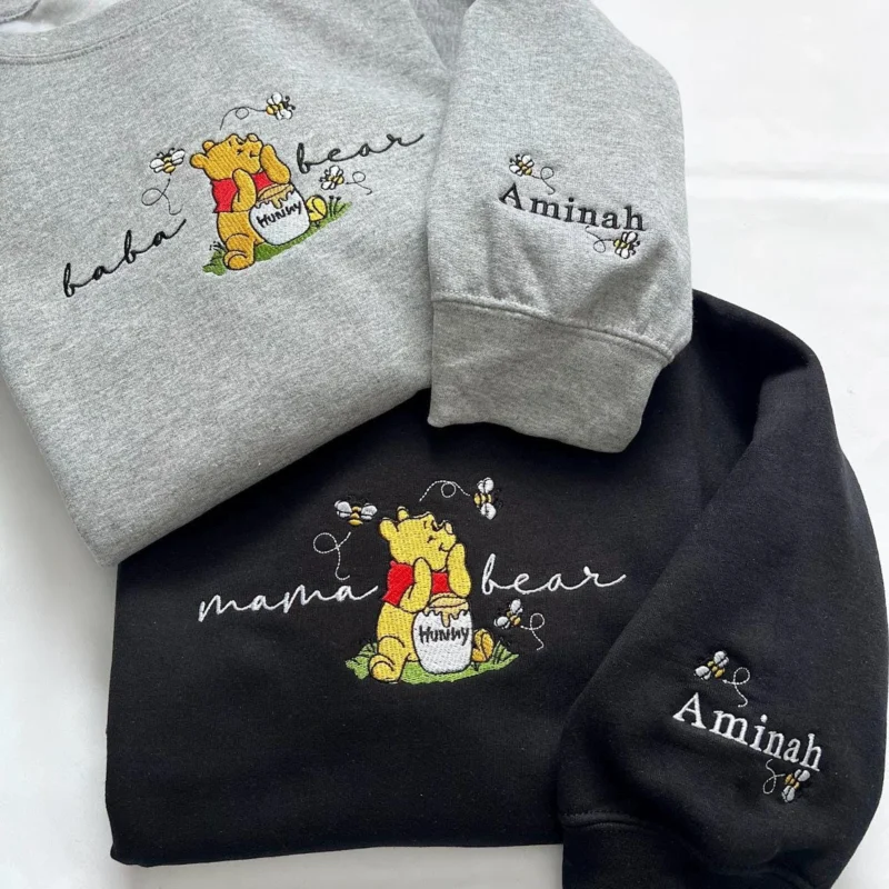 Grey baba bear and black mama bear sweatshirts with a yellow storybook bear, honey pot and bees, and Aminah on each sleeve
