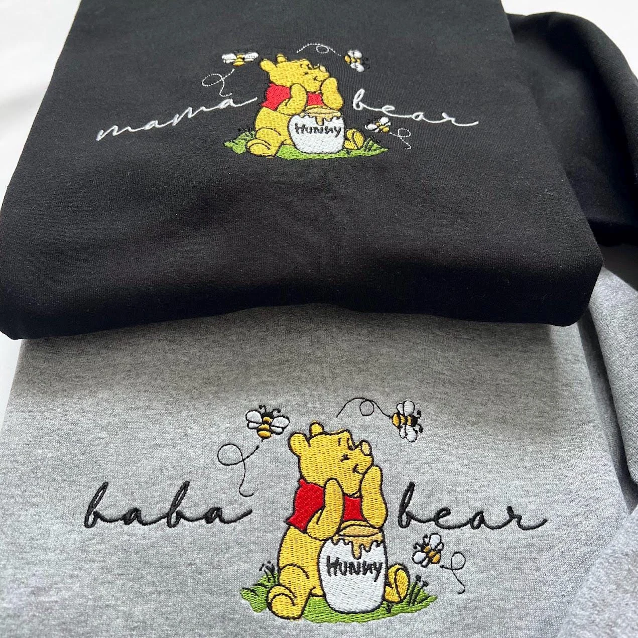 Black mama bear and grey baba bear sweatshirts, each with a yellow bear in a red shirt holding a honey pot