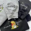 Grey and black sweatshirt sleeves embroidered with the name Aminah and small bees, above the mama bear design