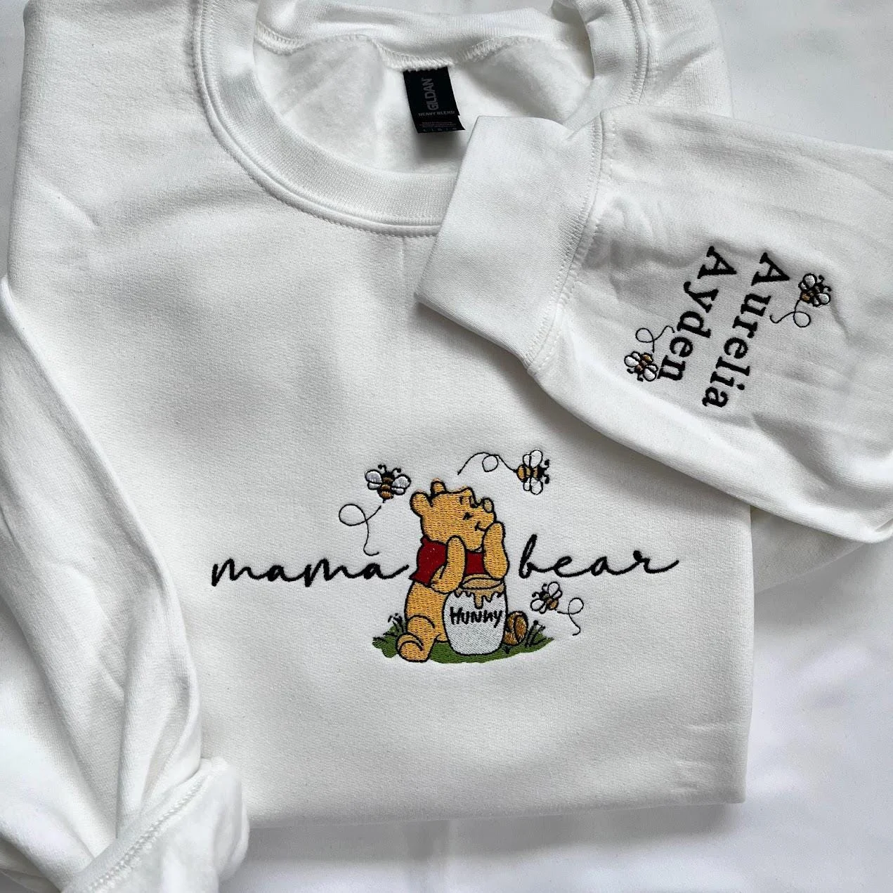 White sweatshirt with mama bear in black script around a yellow bear and Aurelia and Ayden stitched on the sleeve