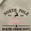 Close-up of the North Pole Milk & Cookies Co. embroidery with a brown reindeer, pink lettering and a small tree