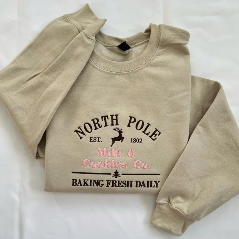 Sand sweatshirt with a North Pole Milk & Cookies Co. bakery sign design, leaping reindeer and Baking Fresh Daily