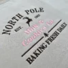 Angled view of brown NORTH POLE lettering, a leaping reindeer, pink Milk & Cookies Co. and BAKING FRESH DAILY