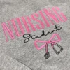 Angled close-up of pink outlined NURSING letters, black Student script and a pink bow tied to a stethoscope