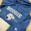 Indigo blue hoodie with a dog portrait, varsity name and est. 2021, plus a small white heart on the sleeve cuff