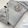 Angled view of a circular BEST Dad EVER badge with red stars and dark grey script stitched on a grey crewneck