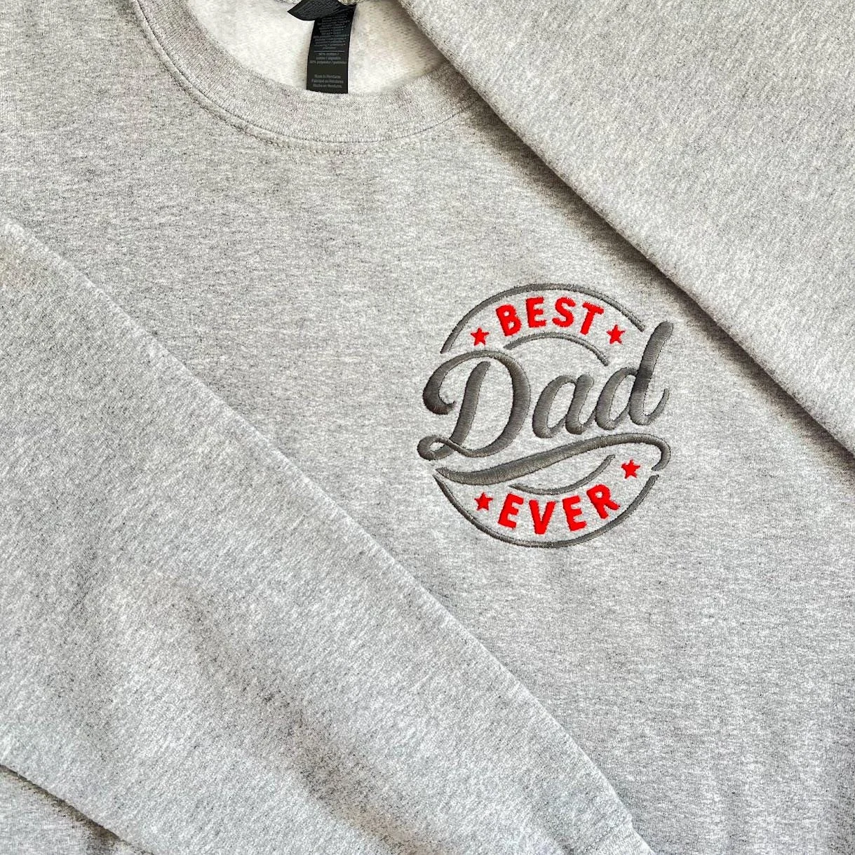 Close-up of the BEST Dad EVER badge embroidery: red letters and stars around Dad in dark grey script