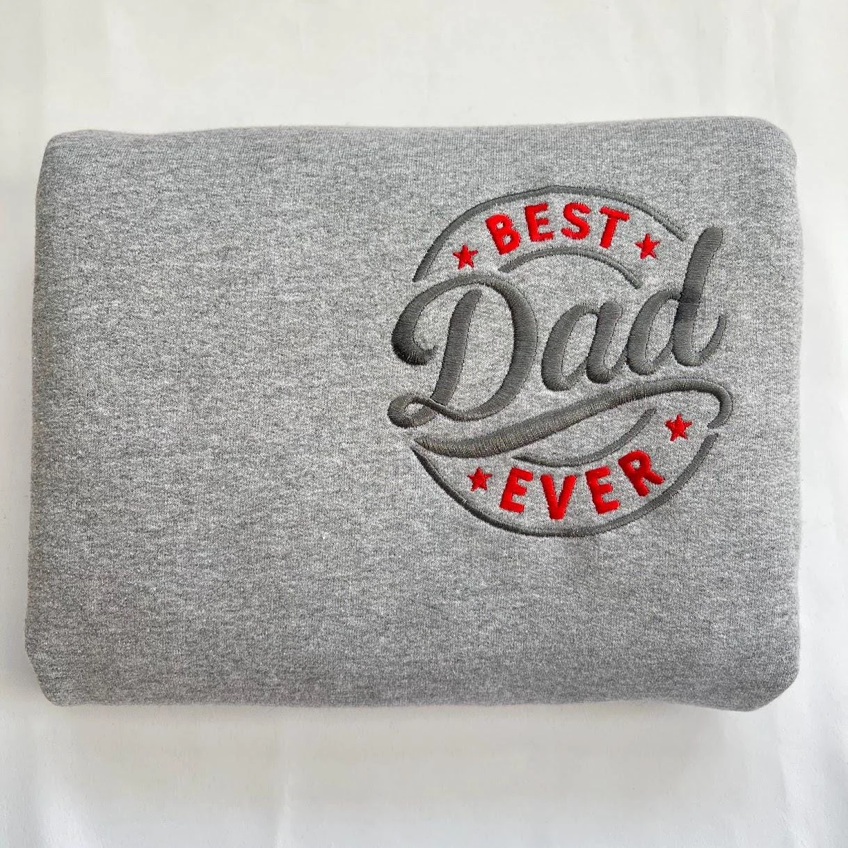 Folded sport grey sweatshirt with the BEST Dad EVER circle badge embroidered in red and charcoal thread