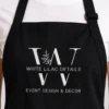 Black bib apron worn over a white tee with a large W leaf logo and business name embroidered in white