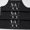 Three black aprons stacked, each with a white W monogram logo with a leaf sprig and an event business name