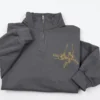 Charcoal quarter-zip with gold line art of family hands in a fist bump, each wrist named Brian, Linda or Ruby