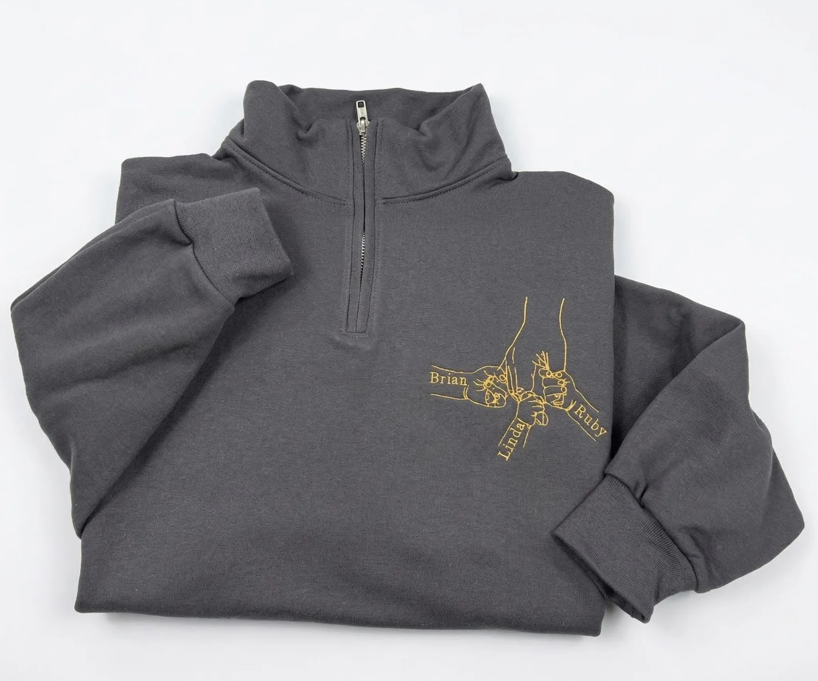 Charcoal quarter-zip with gold line art of family hands in a fist bump, each wrist named Brian, Linda or Ruby