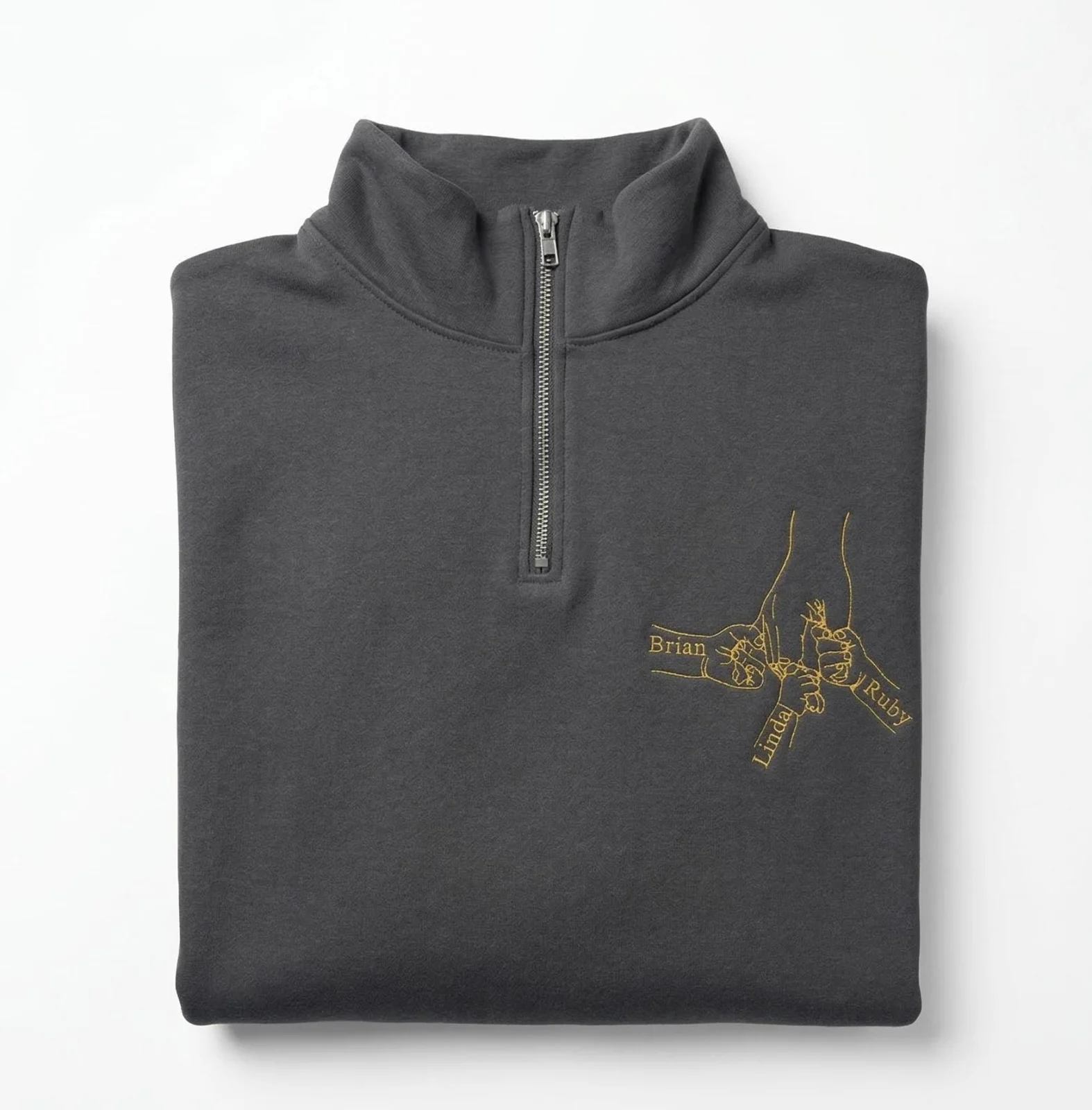 Folded charcoal quarter-zip sweatshirt with the gold family fist bump line art and names on the left chest