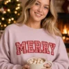 Woman holding hot cocoa in a blush crewneck with MERRY in red gingham applique letters