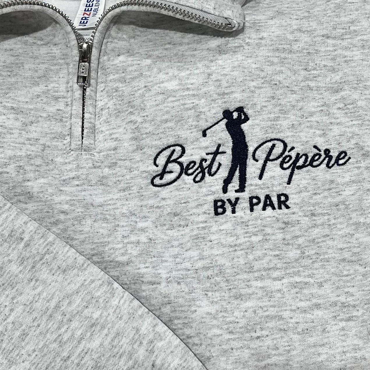 Ash quarter-zip with a navy golfer silhouette mid-swing between Best and Pépère in script, BY PAR below