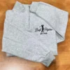 Folded ash quarter-zip on a wooden table with the navy golfer and Best Pépère By Par on the left chest