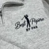 Close-up of a heather grey quarter-zip with the Best Pépère By Par golfer design in navy thread by the zip