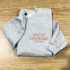 Folded grey sweatshirt on wood with GREAT GRANDMA EST.2026 in coral embroidered capitals