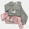 Grey and light pink sweatshirts with outline LOVE letters, a couple portrait making a heart in place of the O, Est.2026